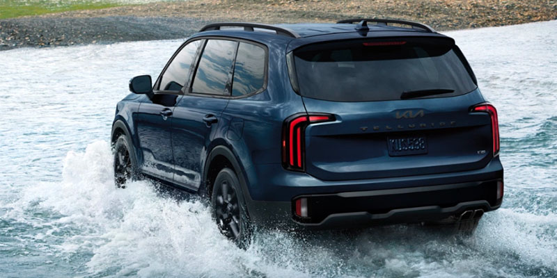 Dark blue 2025 Kia Telluride driving through water near Naples, FL