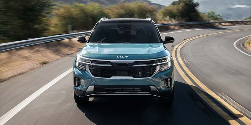 A 2026 Kia Seltos driving on a road, promoting SUV deals in Naples, FL.