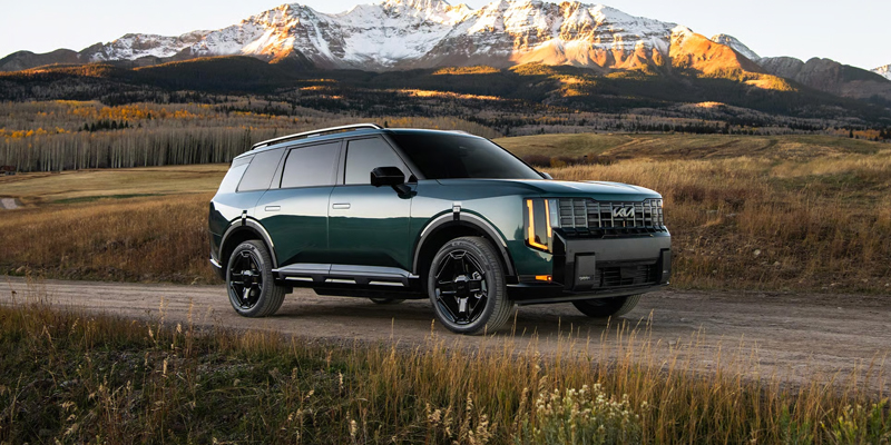 Kia Telluride Hybrid parked in front of a scenic mountain range, showcasing its rugged design and outdoor capability.